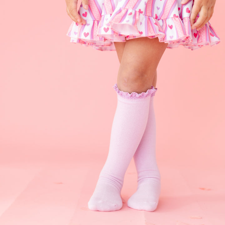 closeup of pastel purple lace top knee high socks paired with pink wallpaper inspired print dress