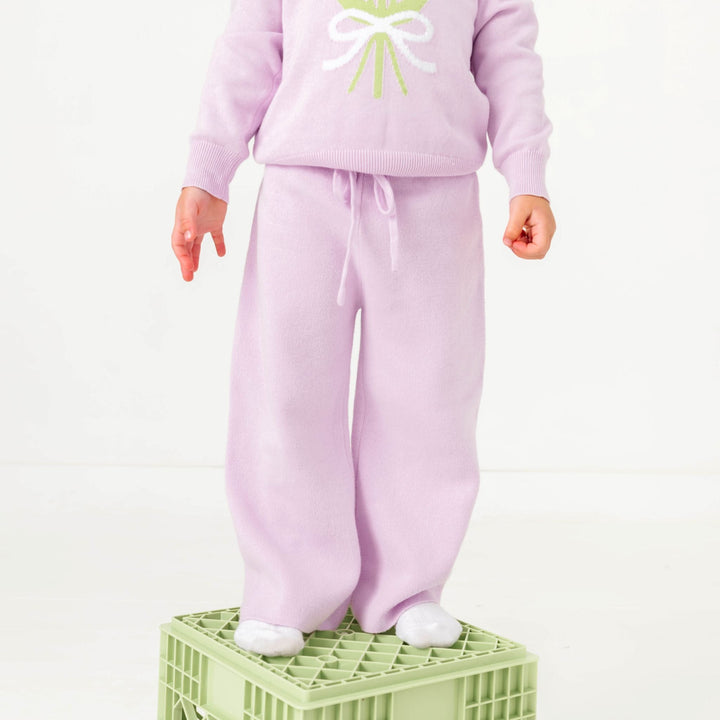 little girl standing on crate in light purple cotton knit sweater pants with matching floral sweater for spring