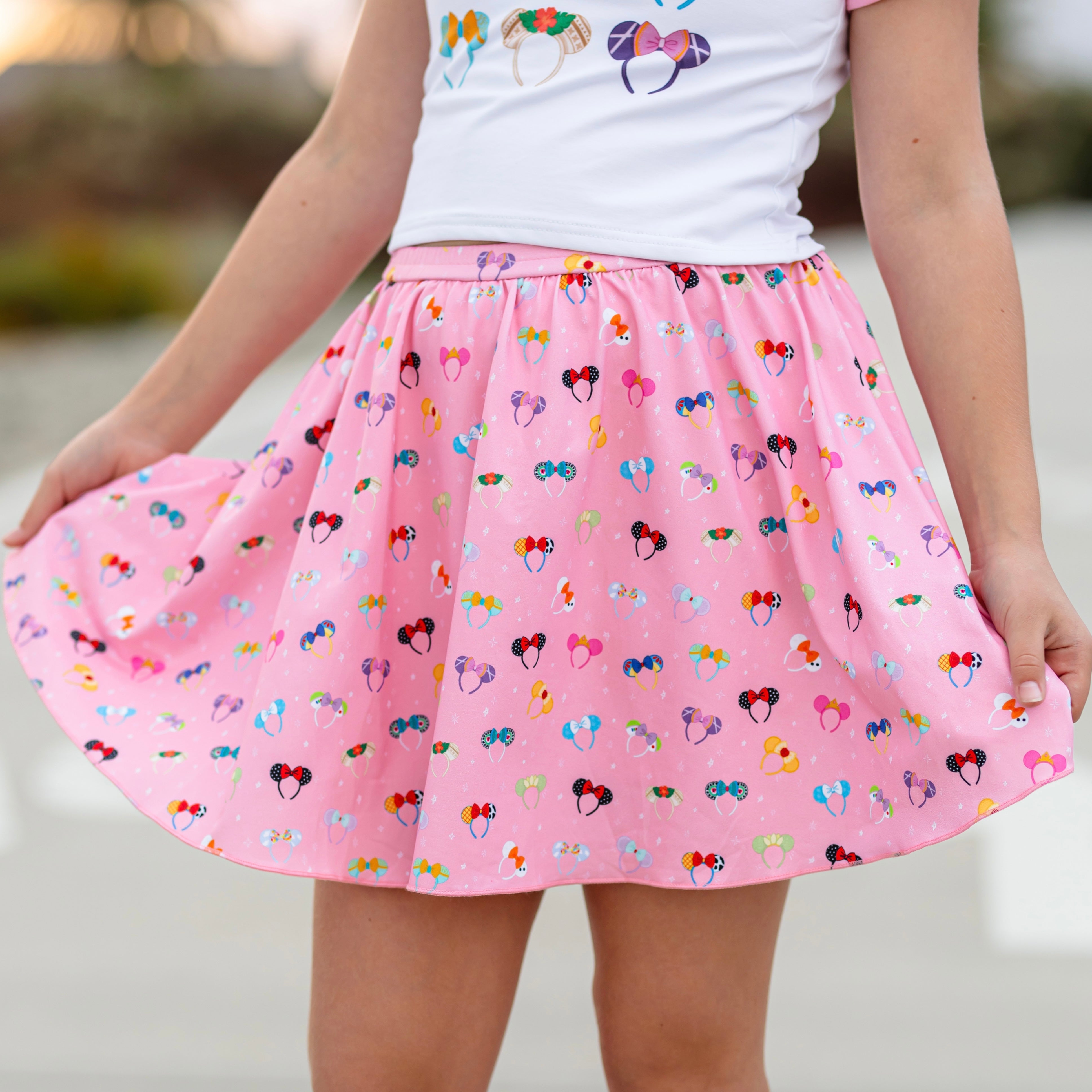 closeup of girl in pink skort with disney inspired character ears paired with matching top