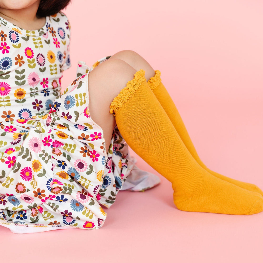 little girl in retro flower dress and matching marigold yellow lsace knee socks