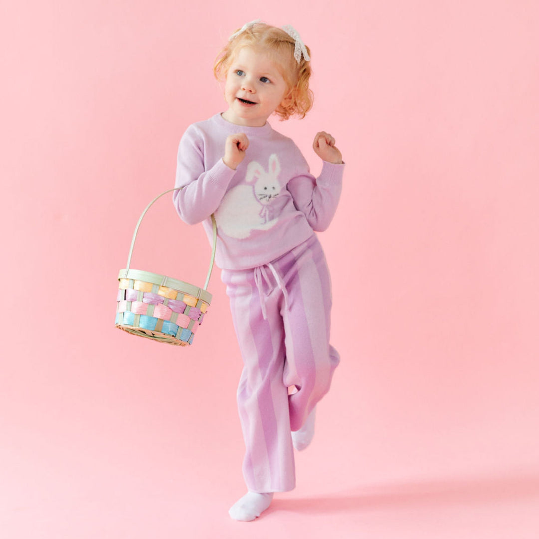 little girl holding Easter basket in lavender knit bunny sweater and matching two tone purple striped sweater pants 