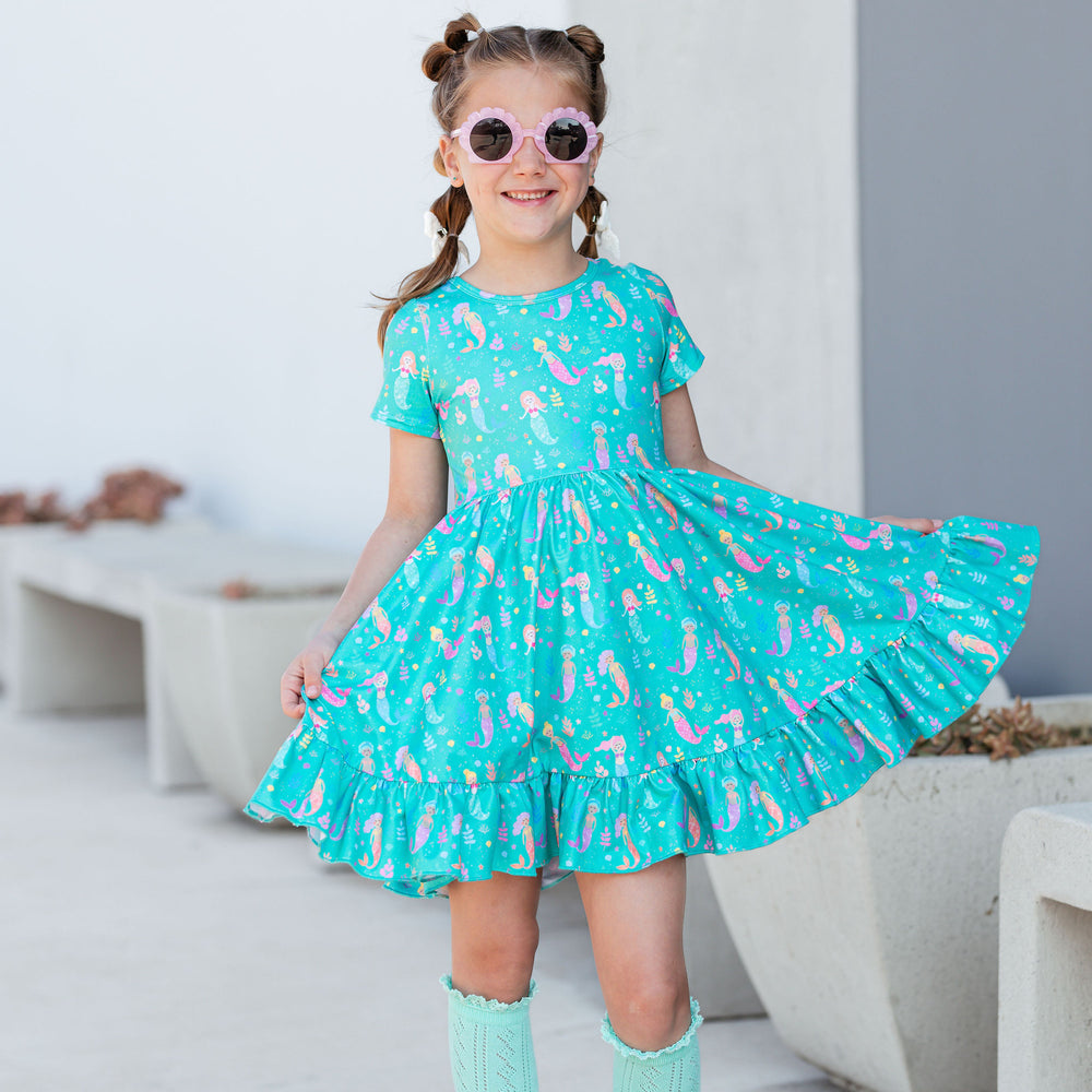 little girl with bubble braids wearing cute mermaid print twirl dress