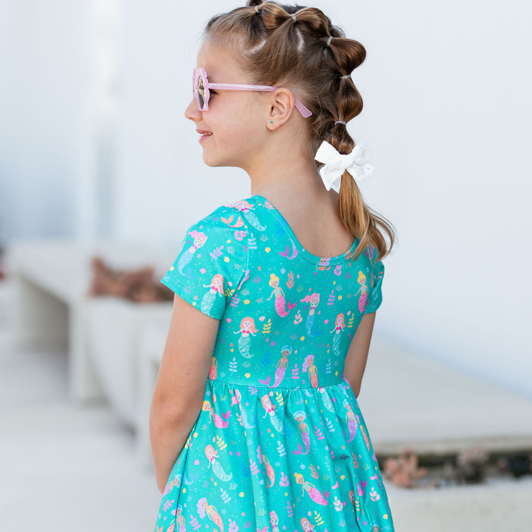 scoop back detail of mermaid dress on little girl wearing sunglasses and bubble braids
