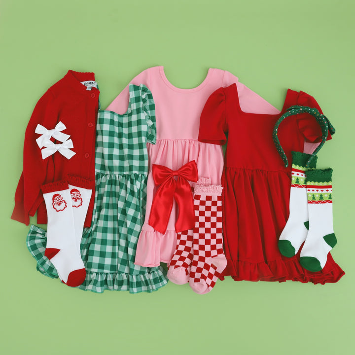 three classic girls' Christmas outfits with matching accessories in red, green and pink 