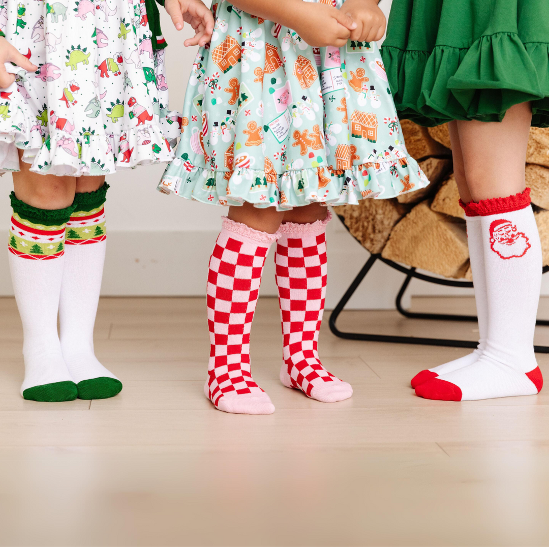 three girls standing together wearing bright and festive christmas knee high socks