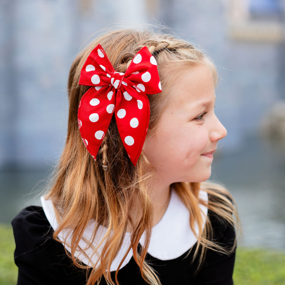 little girl wearing minnie mouse inspired dress and red and white polka dot hair bow