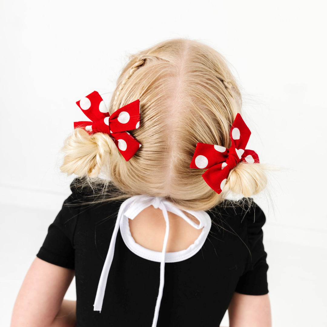 little girl in pigtails with red and white polka dot pigtail bows on clips to match Minnie inspired twirl dress