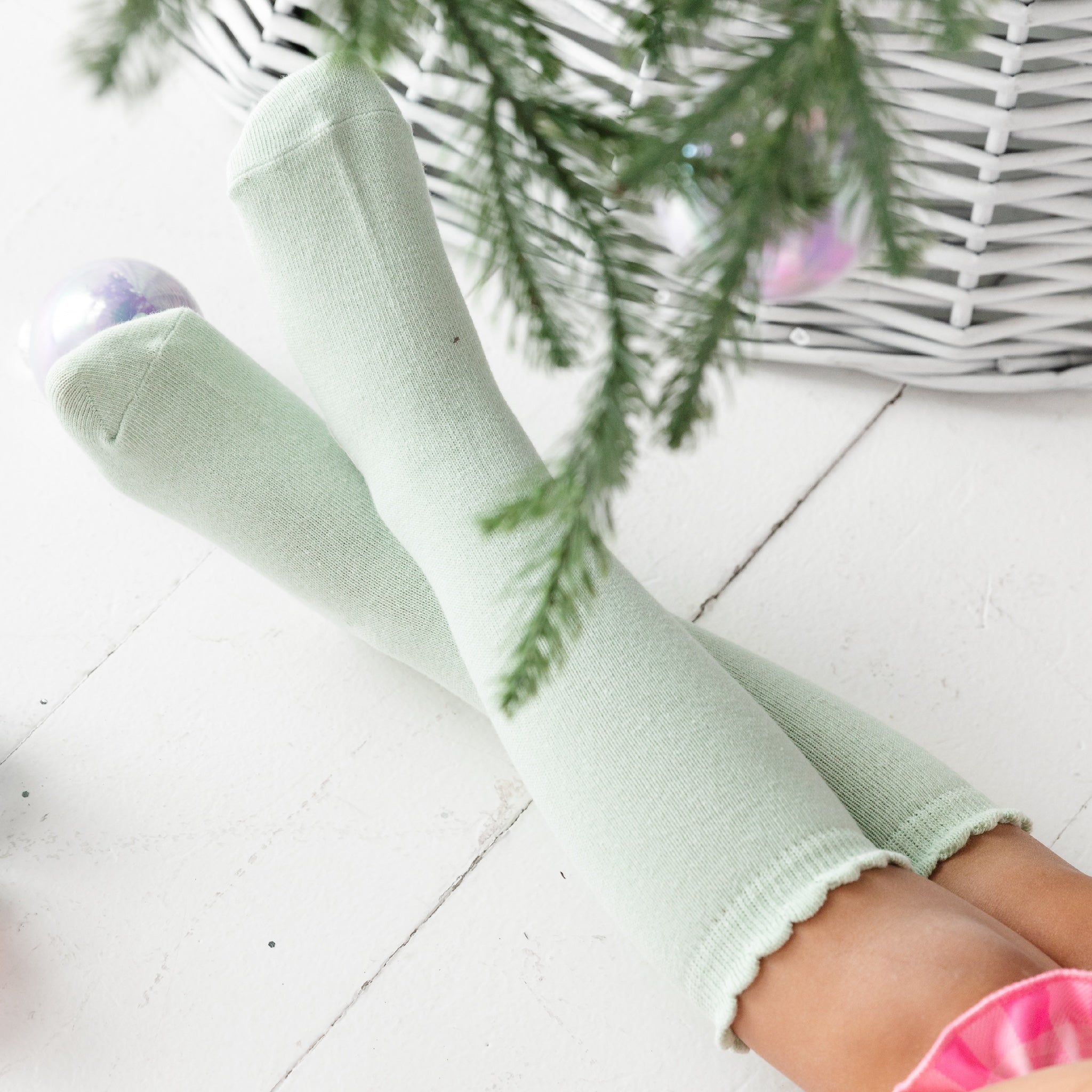 little girls scalloped knee high socks in pastel green under christmas tree