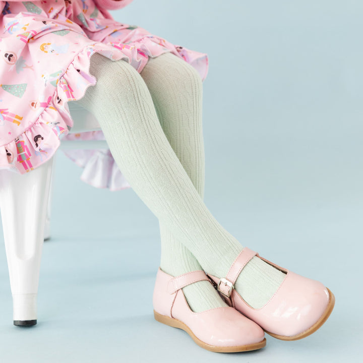 little girl in soft mint cable knit tights to match pastel nutcracker themed Christmas dress