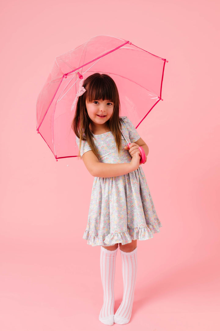 little girl holding pink umbrella in pastel spring floral twirl dress with mint background paired with pink and white striped knee socks