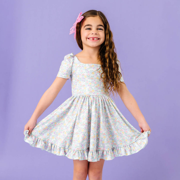 little girl wearing mint green spring twirl dress with pastel floral design paired with pink lace hair bow