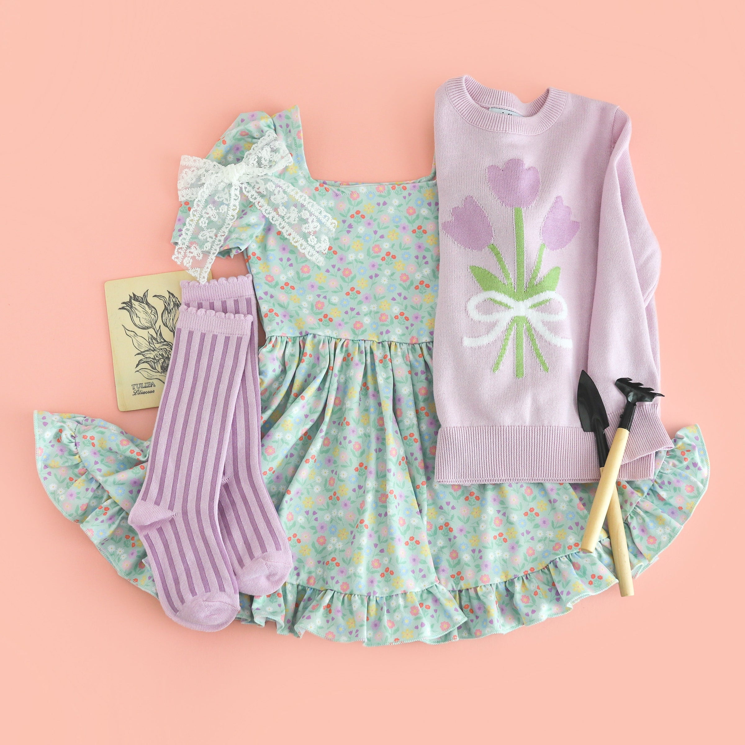 flat lay of styled spring outfit for girls' mint square neck twirl dress with pastel floral print paired with light purple cotton knit tulip sweater and matching lavender striped knee socks and white lace hair bow 
