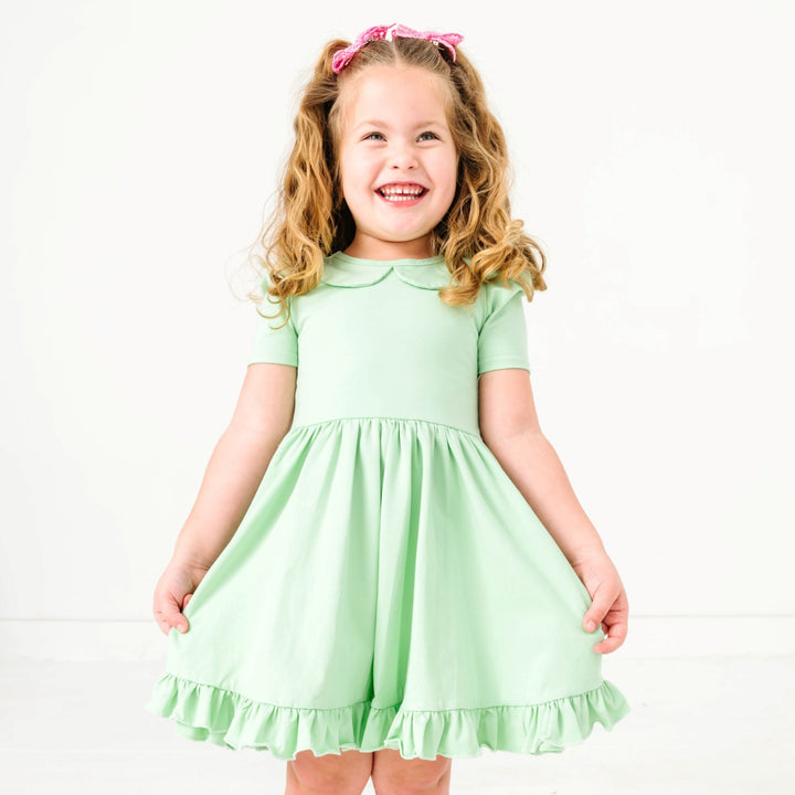 young girl in mint green spring twirl dress with short sleeves and peter pan collar paired with pink lace pigtail bows