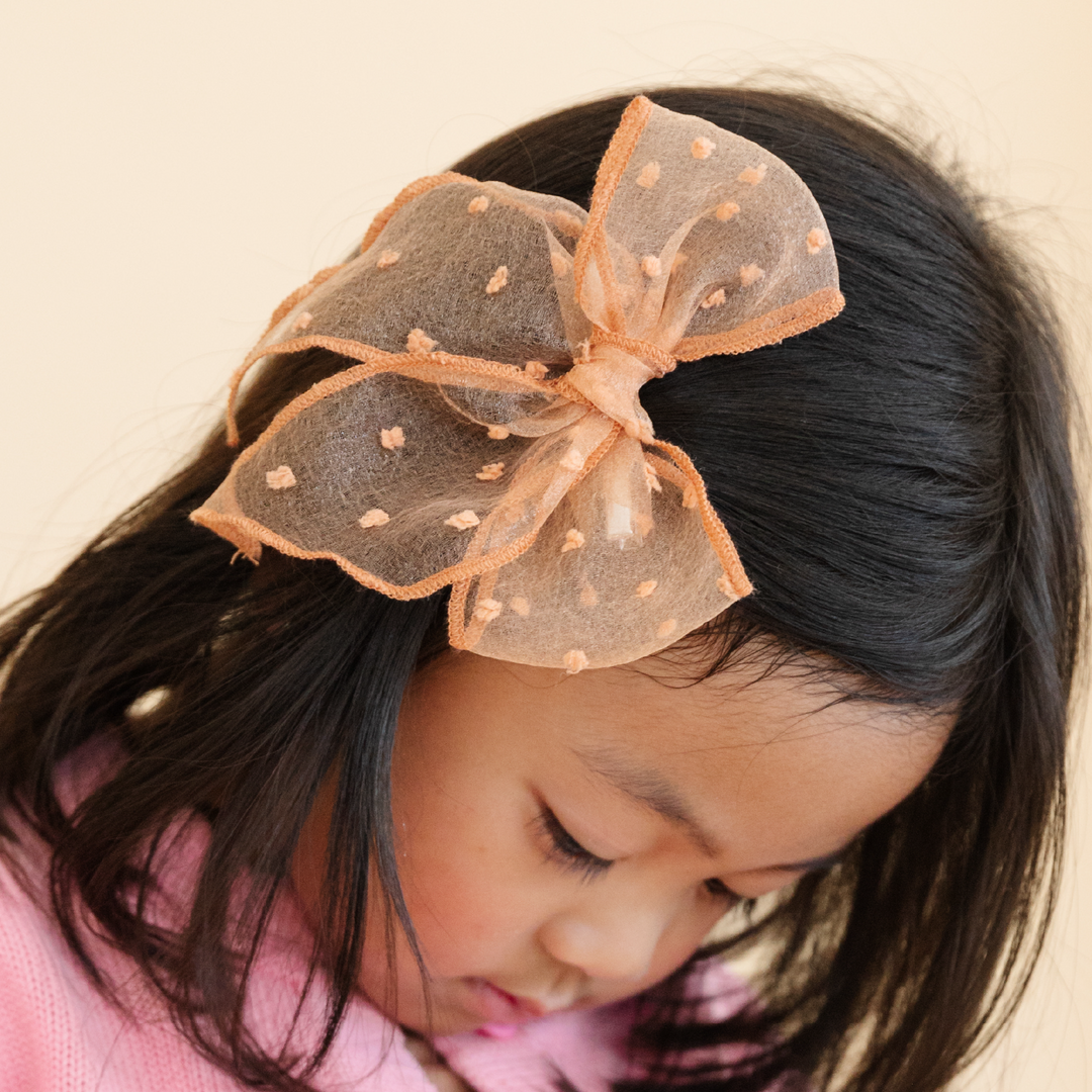 girl wearing golden brown sheer party bow with embroidered dots