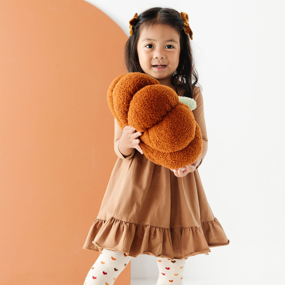 little girl wearing mocha brown twirl dress and fall colored heart pattern tights