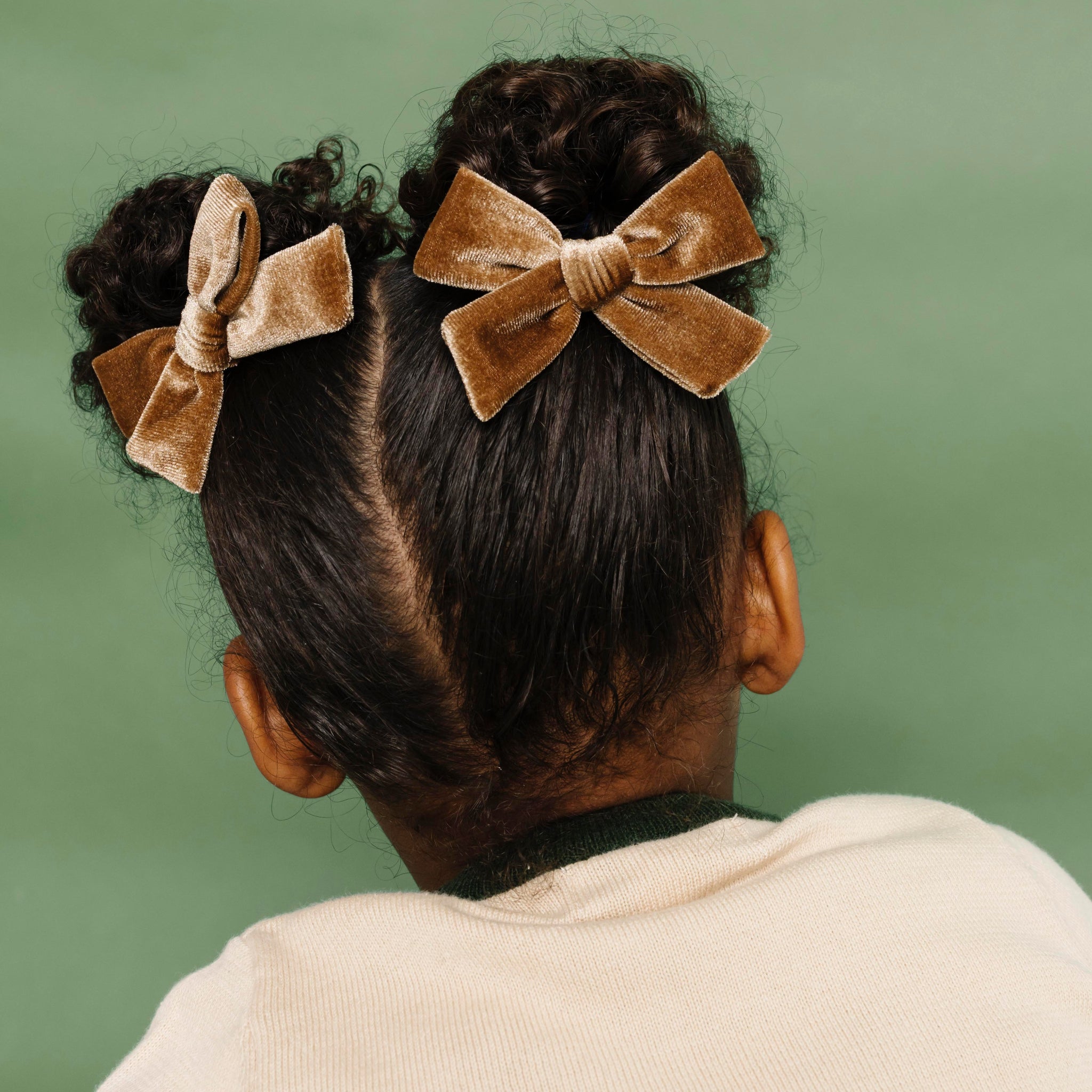 little girl in pigtails with light brown velvet pigtail bows on clips paired with cream holiday sweater
