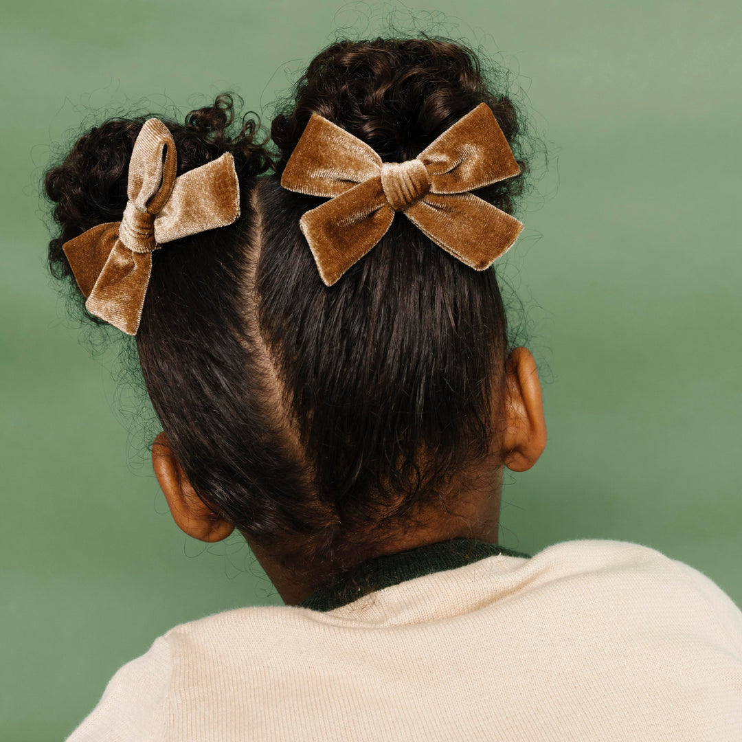 little girl in pigtails with light brown velvet pigtail bows on clips paired with cream holiday sweater