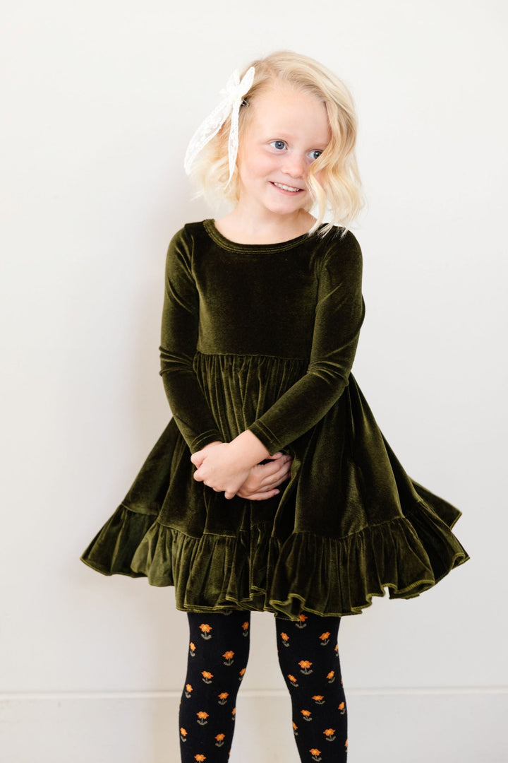 little girl in long sleeve green velvet twirl dress with matching black floral tights and ivory lace bow