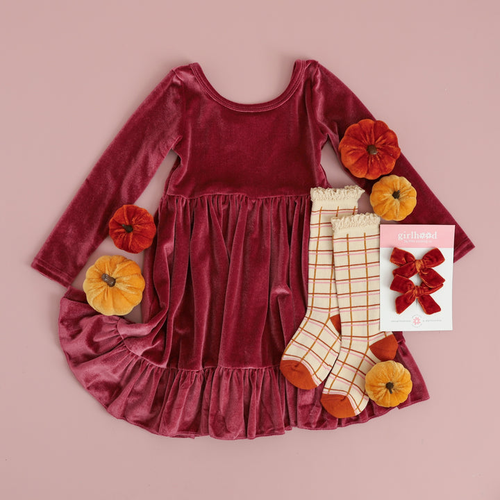 flatlay of mulberry pink velvet dress with fall grid socks and pumpkin velvet pigtail bows