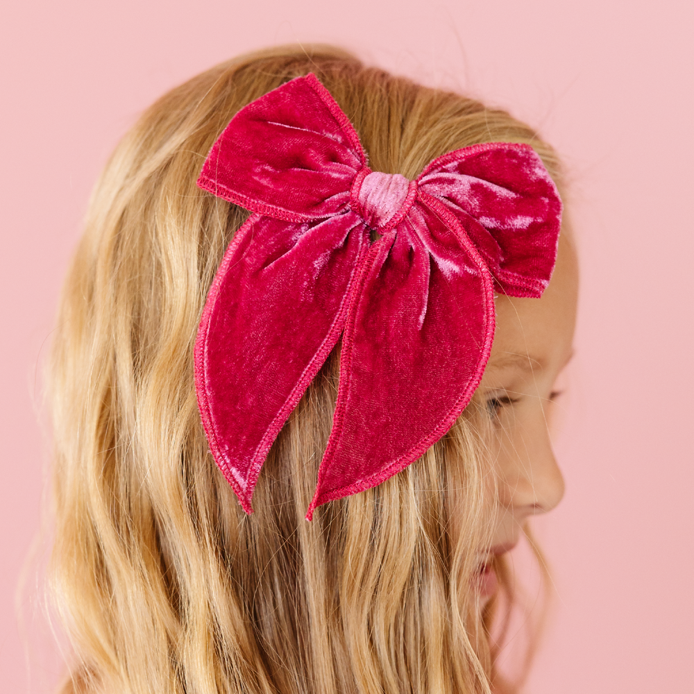 girl wearing mulberry pink velvet hair bow in front of pink background