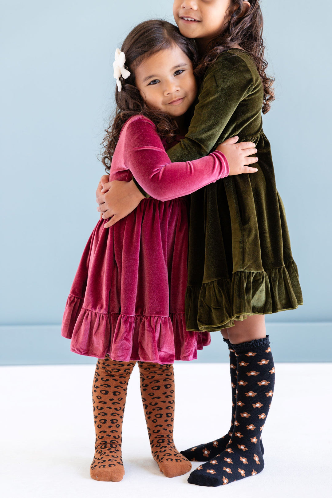 little girls in pink and green long sleeve fall velvet dresses with matching tights and knee highs