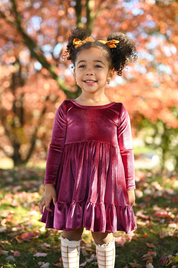 little girl in front of fall foliage in pink velvet twirl dress with harvest grid knee highs and matching mustard velvet pigtail bows on clips