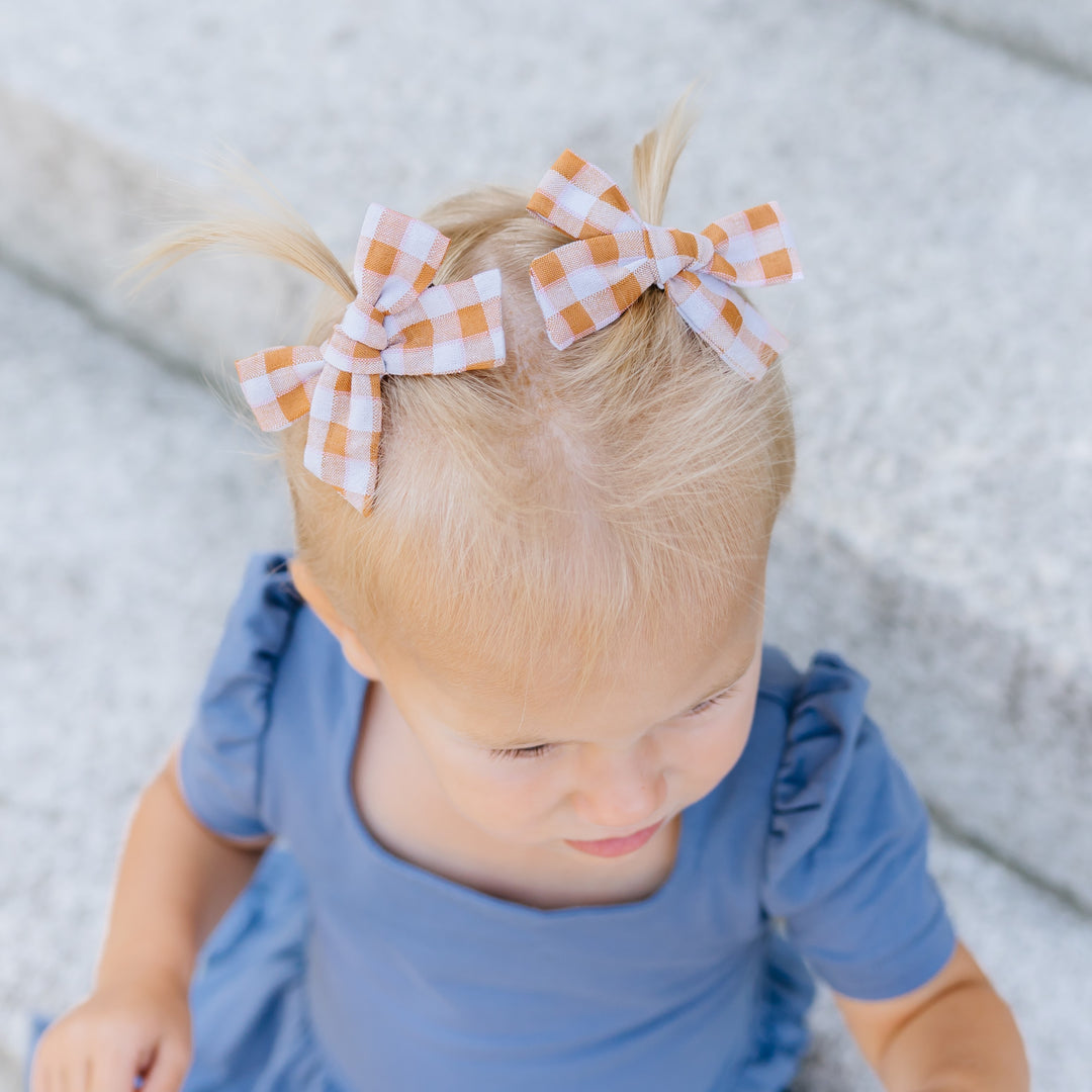 little girls pigtail hairbows in mustard and cream gingham print paired with blue twirl dress for fall