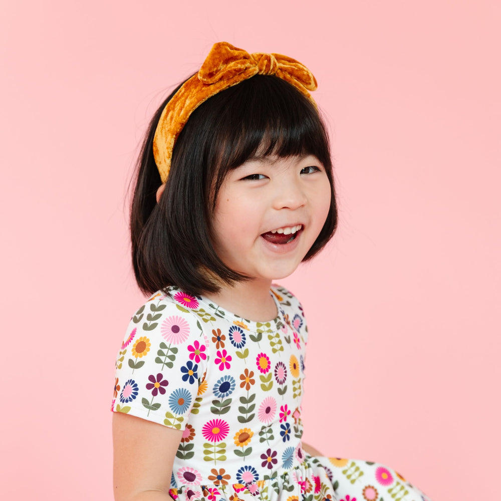 little girl in bright multicolor fall floral dress and matching velvet headband in mustard yellow