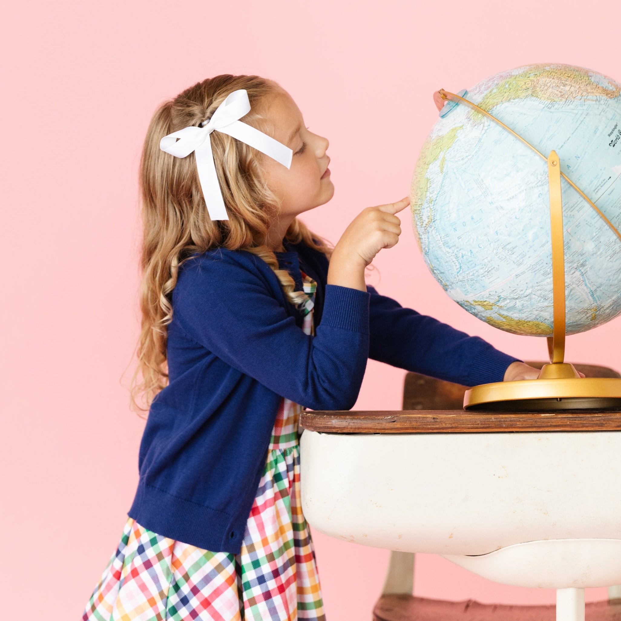 girl wearing cotton knit navy blue cardigan with button front and scalloped trim with matching rainbow gingham dress in back to school photoshoot