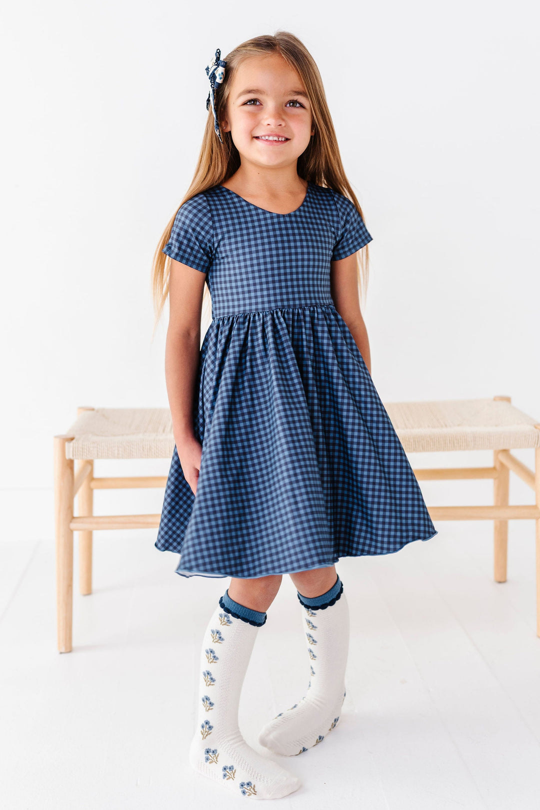 girl wearing navy blue gingham dress with matching floral knee high socks