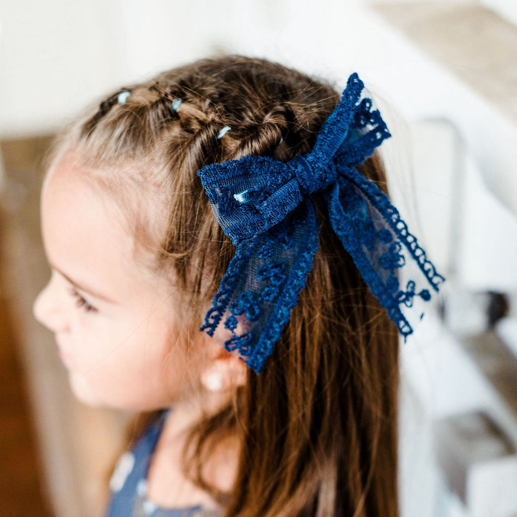 little girl in blue floral dress with matching navy lace hair bow on alligator clip