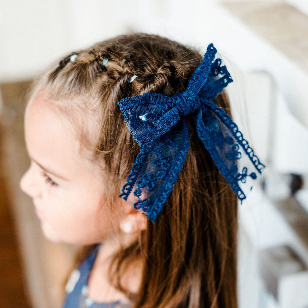 little girl in blue floral dress with matching navy lace hair bow on alligator clip