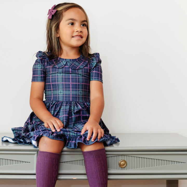 little girl sitting wearing blue plaid twirl dress and plum purple cable knit knee high socks