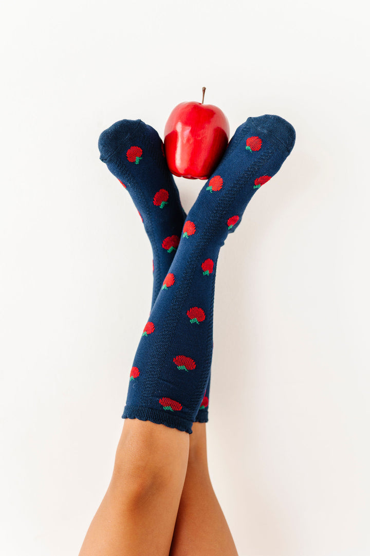 feet wearing navy apple knee high socks holding red apple