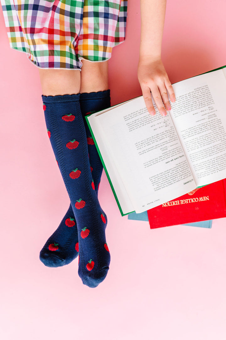 girl reading book wearing navy apple knee high socks