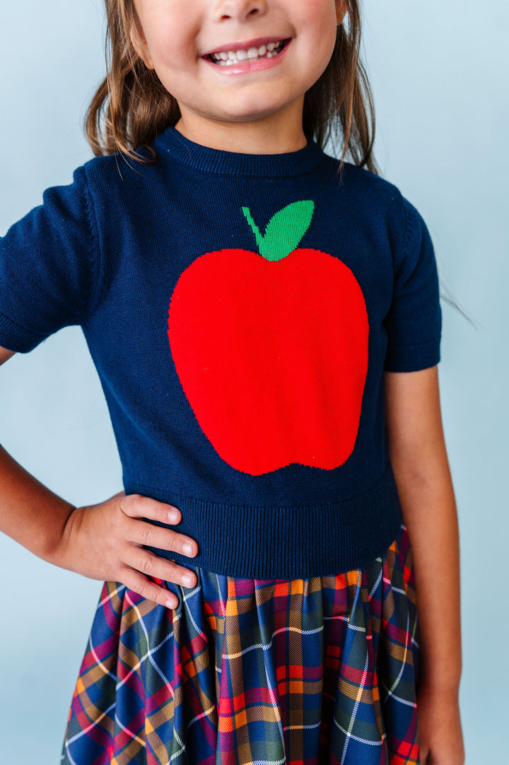 girl wearing navy short sleeve sweater with big red apple