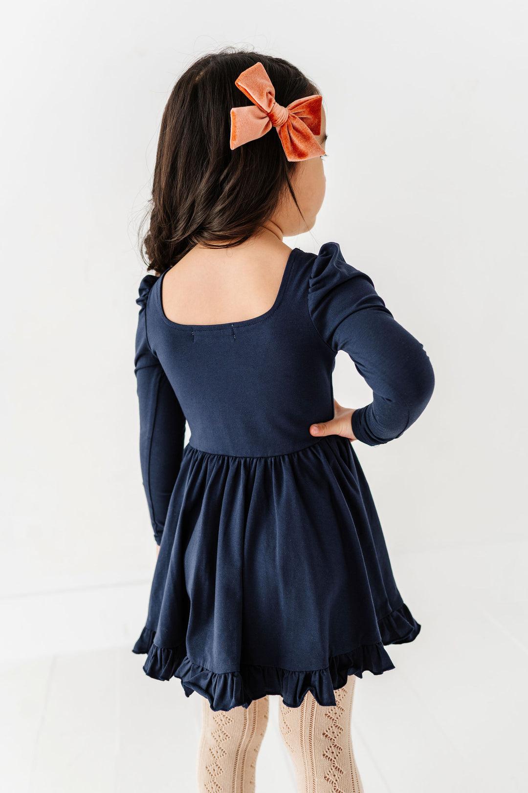 little girl wearing long sleeve navy twirl dress with square neckline