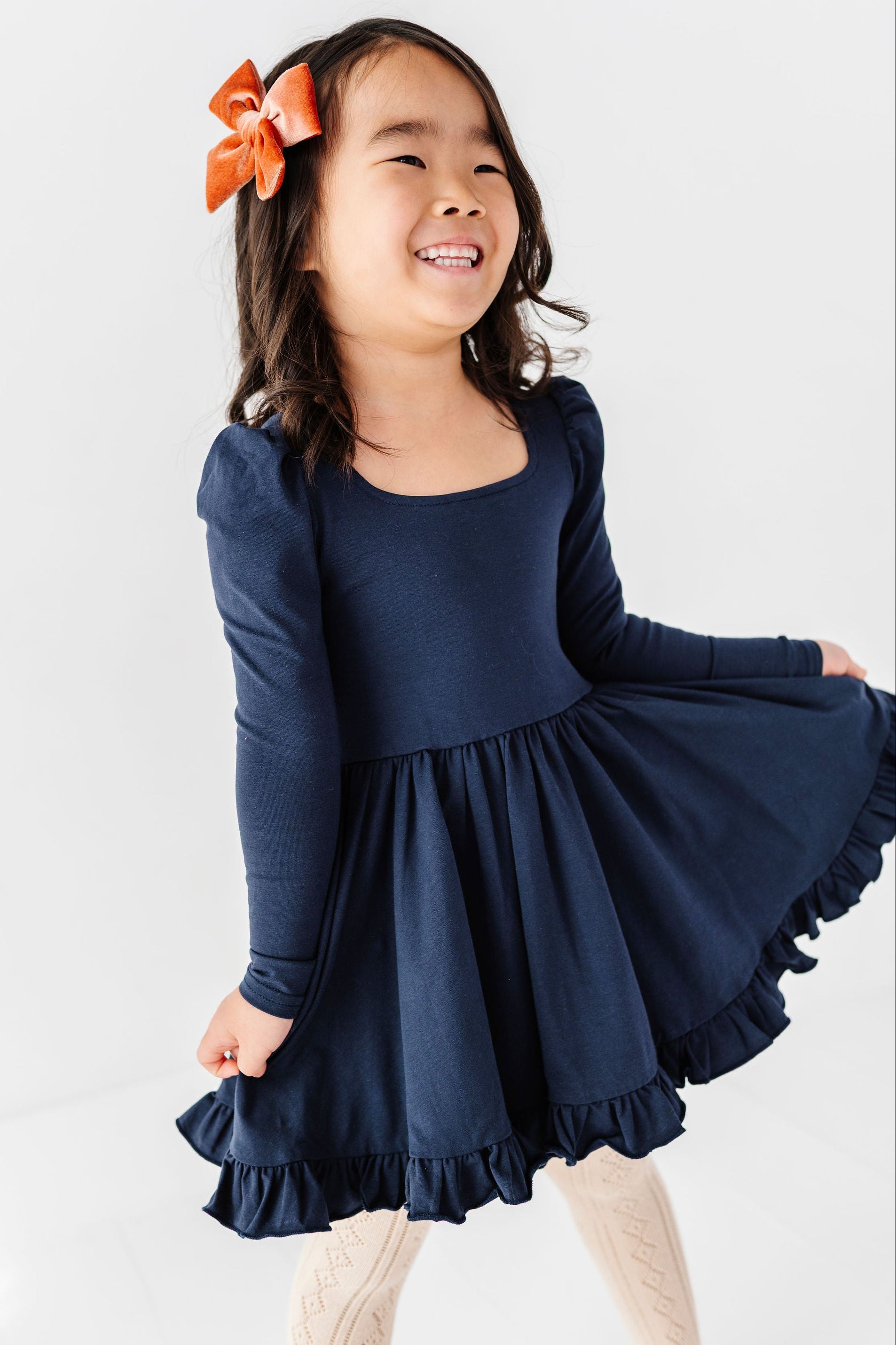 little girl wearing long sleeve navy twirl dress with square neckline