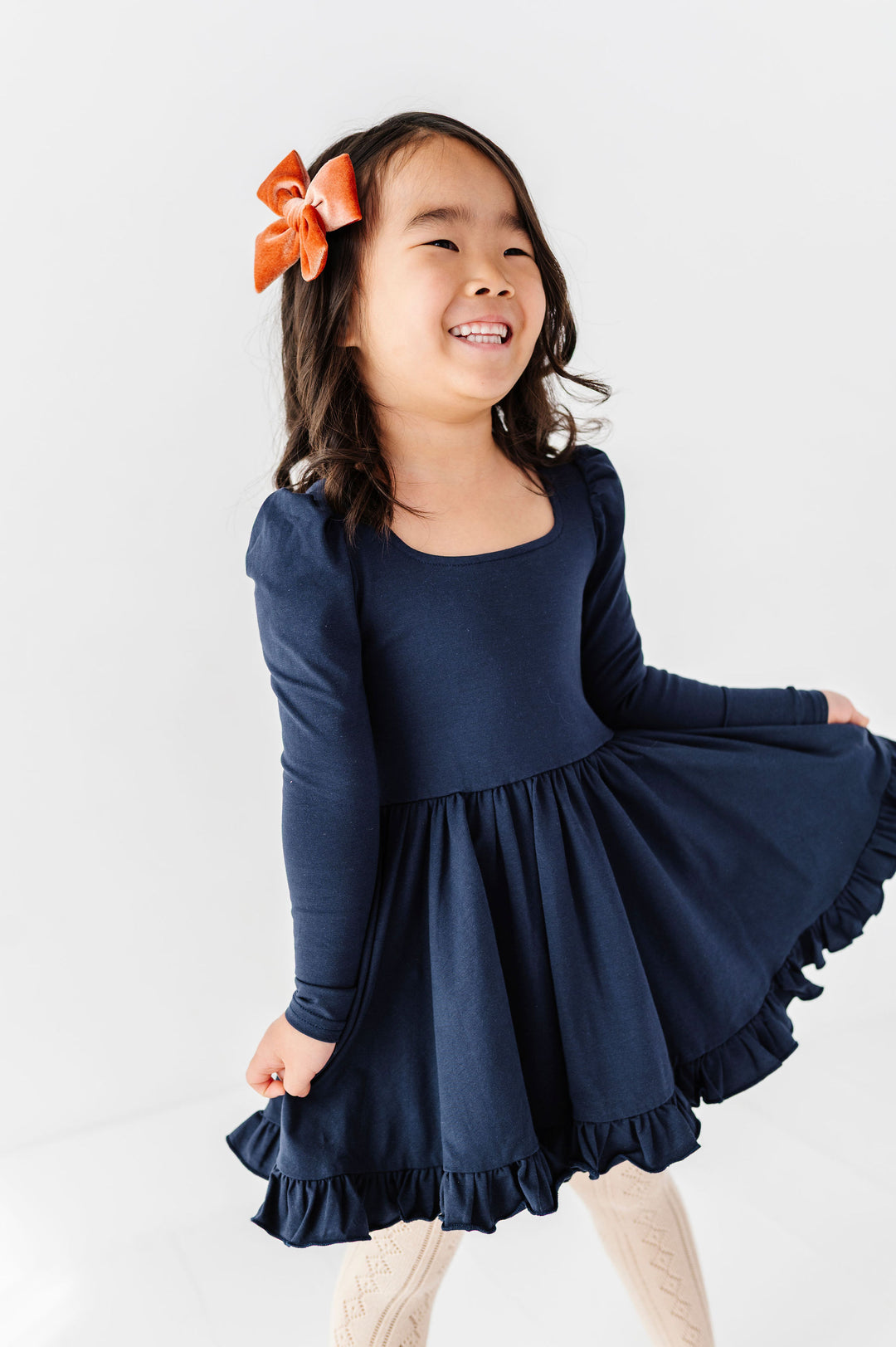 little girl wearing long sleeve navy twirl dress with square neckline