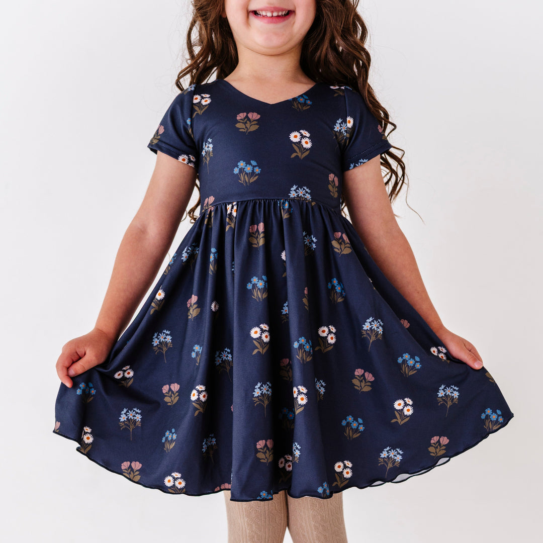 little girl in navy v-neck twirl dress with lettuce trim hem and fall wildflower print