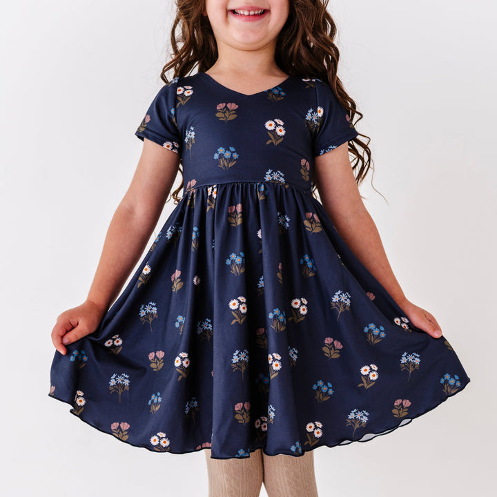little girl in navy v-neck twirl dress with lettuce trim hem and fall wildflower print
