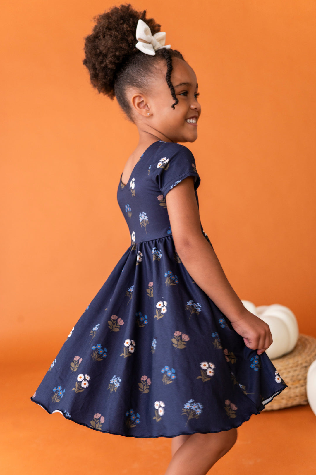 little girl twirling in dark blue floral twirl dress with v-neck design and short sleeves