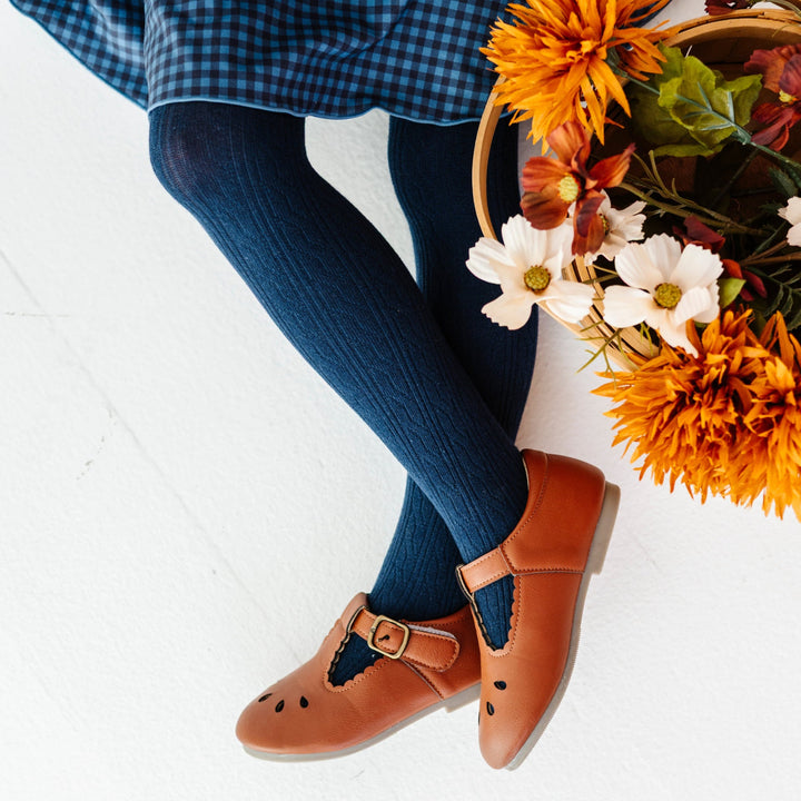 closeup of navy tights on little girl with fall flower basket paired with blue gingham twirl dress and brown mary jane shoes