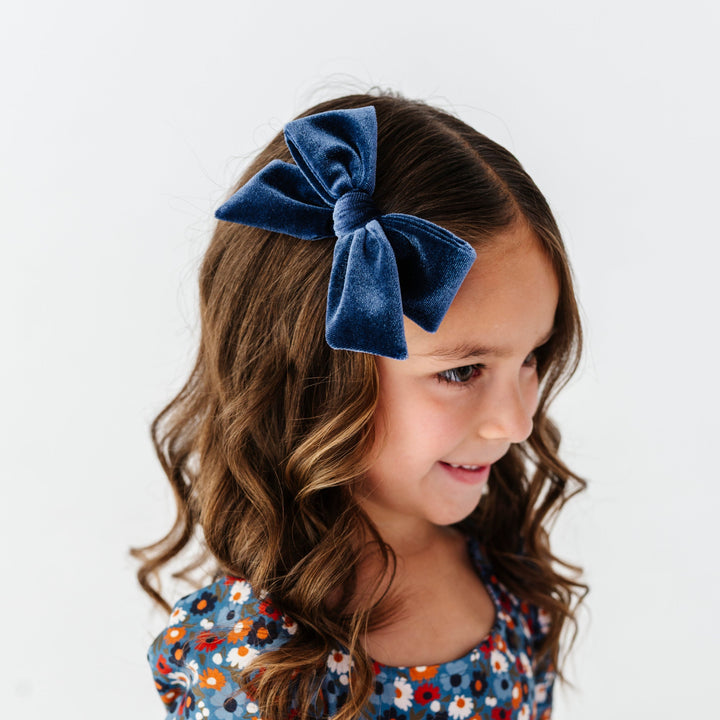 little girl wearing navy velvet hair bow on clip paired with matching blue floral fall dress