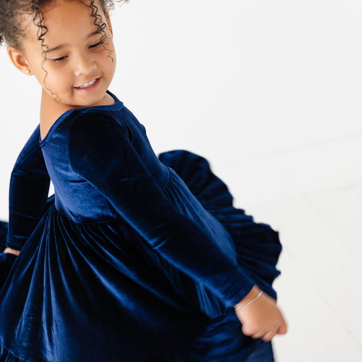 girl twirling in navy velvet party dress