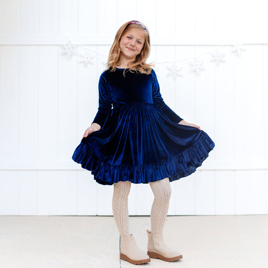 girl wearing navy velvet twirl dress with cream pointelle knit tights