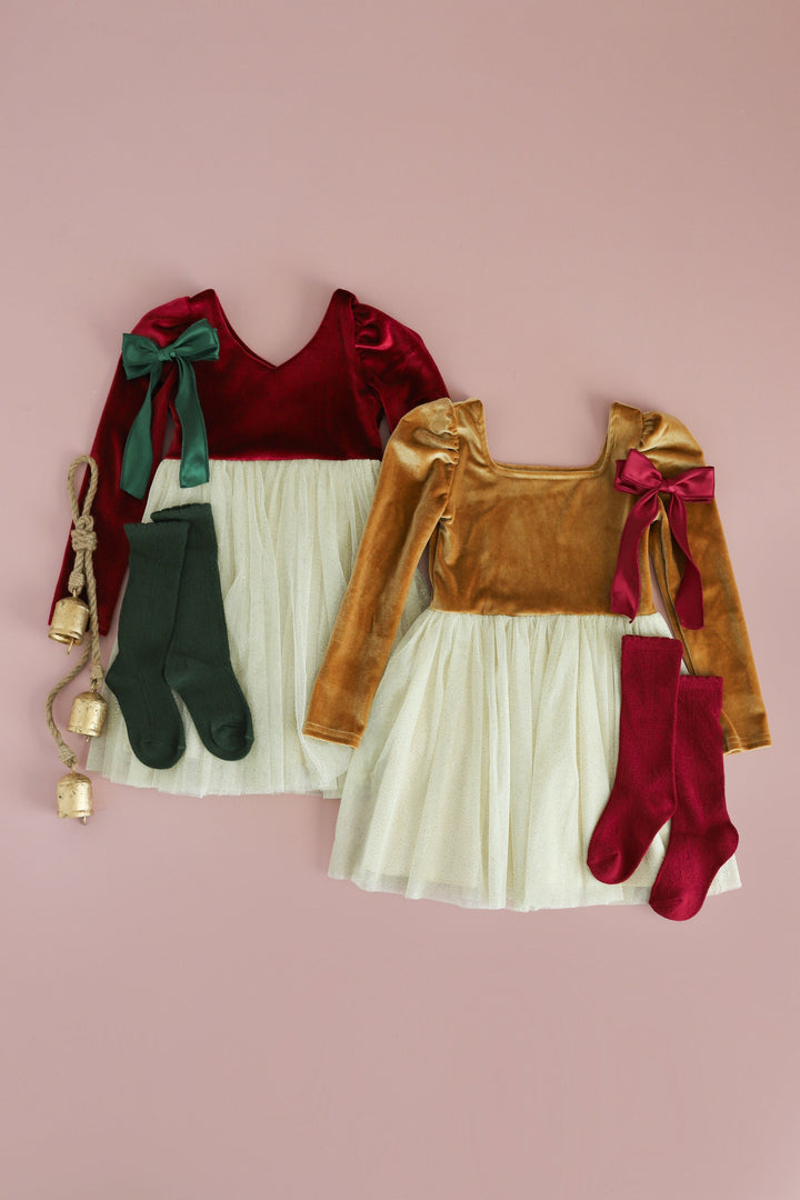 flatlay of girls velvet christmas dresses in gold, crimson red and cream