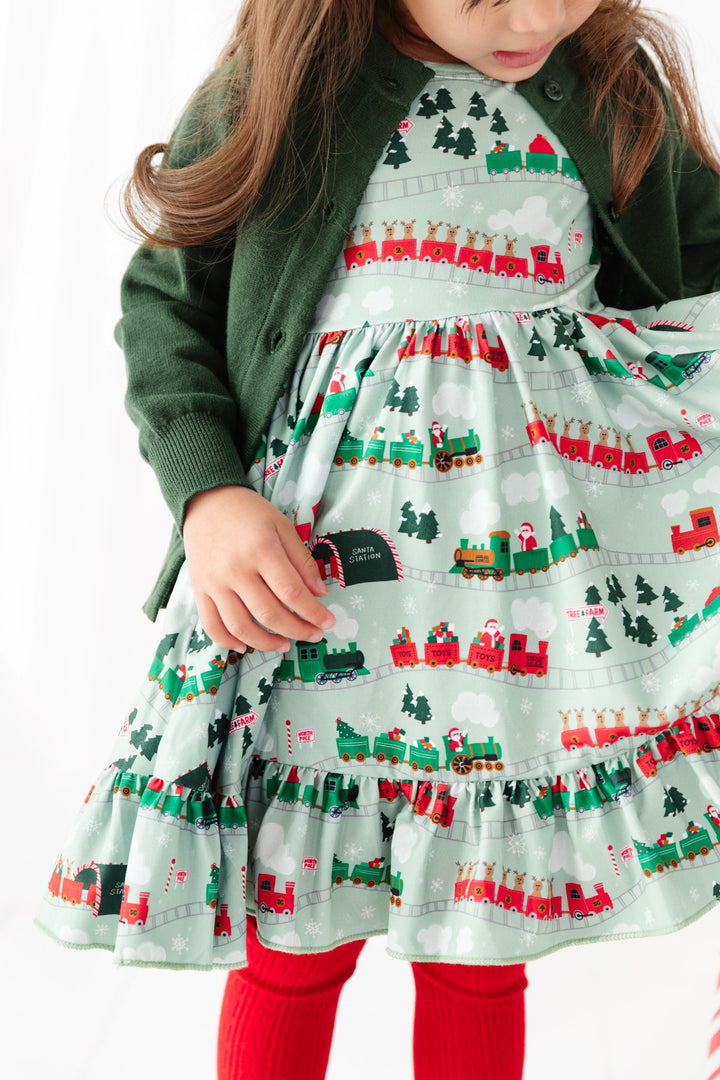 little girl in Santa train dress with North Pole theme and matching green and red accessories