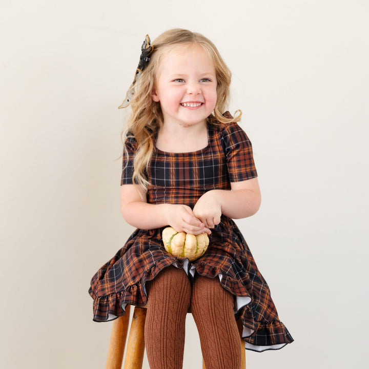 little girl in harvest themed fall plaid twirl dress and matching brown cable knit tights 