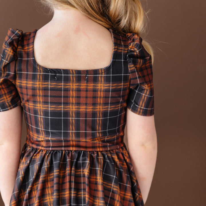 back veiw of square neckline on girl's black and brown fall plaid twirl dress